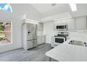 Bright kitchen features stainless steel appliances, white cabinets, and a window overlooking the front yard at 905 Hatteras Ave, Minneola, FL 34715