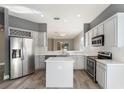 Open-concept kitchen with stainless steel appliances, white cabinetry, and an island, creating a modern and functional space at 10812 Woodchase Cir, Orlando, FL 32836