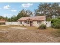 Single-story house with brown metal roof and red front door, surrounded by trees and a yard at 513 Seminole Ave, Fruitland Park, FL 34731