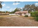 Single-story house with brown metal roof and red front door, surrounded by trees and a yard at 513 Seminole Ave, Fruitland Park, FL 34731