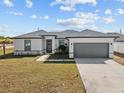 Newly built home with gray garage door and landscaped lawn at 803 Fraser Dr, Poinciana, FL 34759