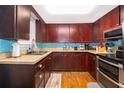 Kitchen with dark wood cabinets, light blue backsplash, and stainless steel appliances at 1601 New York Ave., St Cloud, FL 34769