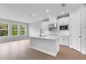 Spacious kitchen with white cabinets, stainless steel appliances, an island, and lots of natural light from the large windows at 2983 Arranmore Dr, Ormond Beach, FL 32174
