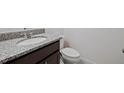 Powder room with a granite countertop, wood cabinetry, and white toilet at 7100 Cherry Pasture Rd, Groveland, FL 34736