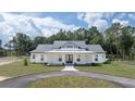 White farmhouse exterior with gray roof, landscaping, and driveway at 10750 Sw 110Th St, Dunnellon, FL 34432