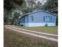 Gray manufactured home with white skirting, wooden steps, and a long driveway at 13811 County Road 109D, Lady Lake, FL 32159
