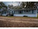 Gray manufactured home with white skirting, wooden steps, and a long driveway at 13811 County Road 109D, Lady Lake, FL 32159