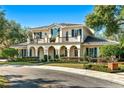 Two-story house with a balcony, arched entryway, and manicured lawn at 1000 Via Tuscany Oaks Way, Winter Park, FL 32789