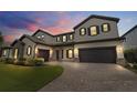 Two-story house with stone accents and a three-car garage at dusk at 11769 Hampstead St, Windermere, FL 34786