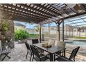Outdoor dining area featuring a pergola, ceiling fan, stone wall, fire pit, and views of the backyard at 14190 Dove Hollow Dr, Orlando, FL 32824