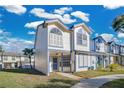 Two-story townhome with light beige siding, blue trim, and a manicured lawn at 2823 Boulder Falls Ct, Apopka, FL 32703