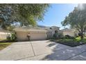 House exterior featuring a three-car garage and lush landscaping at 2647 Aloma Oaks Dr, Oviedo, FL 32765