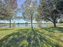 Spacious backyard with a lake view, lush grass, and large trees at 250 Bayou Bend Rd, Groveland, FL 34736