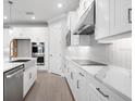Modern kitchen showcasing white cabinetry, stainless steel appliances, marble countertops, and a stylish range hood at 2975 Arranmore Dr, Ormond Beach, FL 32174