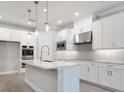 Contemporary kitchen with white cabinets, stainless appliances, marble countertop island, and pendant lighting at 2975 Arranmore Dr, Ormond Beach, FL 32174