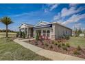 One story home with gray siding, stone accents, and palm tree at 9154 Harris Hawk Dr, Leesburg, FL 34788