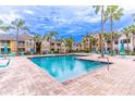 Community swimming pool surrounded by a deck, lounge chairs, palm trees, and apartment buildings at 1057 S Hiawassee Rd # 1911, Orlando, FL 32835