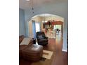 Living room with hardwood floors, view of kitchen, and comfy seating at 16307 Old Ash Loop, Orlando, FL 32828