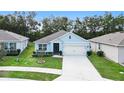 Single-story home with light blue exterior, two-car garage, and landscaped front yard at 3627 Crimson Clover Dr, Mount Dora, FL 32757