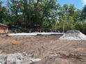 New home construction featuring a concrete slab foundation surrounded by a lush, wooded landscape at 25122 Ensley Rd, Sorrento, FL 32776