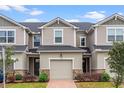 Two-story townhome with light beige siding, dark gray roof, and a two-car garage at 1153 Seaside Mist Trl, Kissimmee, FL 34747