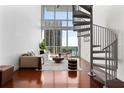 Spacious living room boasts large windows with a view, spiral staircase, and hardwood floors at 150 E Robinson St # 1011, Orlando, FL 32801