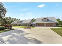 A charming home with a light-colored metal roof, large driveway and lush green lawn and landscaping at 12788 Gillard Rd, Winter Garden, FL 34787