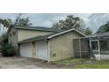 Back of house showing a two-car garage and screened pool area at 1450 Warrior Trl, Deltona, FL 32725