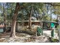 Charming exterior view of a stone home, complete with a covered porch and verdant greenery at 221 Se 125Th Terrace Rd, Silver Springs, FL 34488