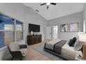 A staged main bedroom with light gray walls, vaulted ceiling, television, and a large window with natural light at 326 Morning Creek Cir, Apopka, FL 32712