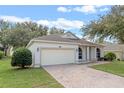 One-story house with a white exterior, a two-car garage, and a landscaped lawn at 15318 Harvest Blvd, Clermont, FL 34714