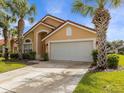 Tan house with a two-car garage, palm trees, and driveway at 164 Sevilla Ave, Davenport, FL 33897