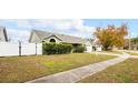Green house exterior with a white fence and large tree in the background at 1747 Lady Slipper Cir, Orlando, FL 32825