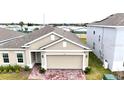 Tan two-story house with a two-car garage and a brick driveway at 3653 Yarian Dr, Haines City, FL 33844
