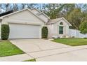 Tan house with white garage door and landscaping at 562 Eagle Pointe S, Kissimmee, FL 34746