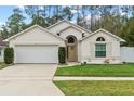 Tan house with white garage door, landscaping, and a white fence at 562 Eagle Pointe S, Kissimmee, FL 34746