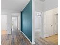 Inviting hallway with wood-look flooring, a teal accent wall, and doorways leading to various rooms at 1504 Finchburg St, Minneola, FL 34715