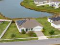 One-story home with solar panels, situated near a lake and other houses at 306 Quarry Rock Cir, Kissimmee, FL 34758