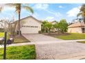 House with a beige exterior, lush landscaping, and a brick driveway at 3181 Winding Trl, Kissimmee, FL 34746