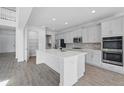 Modern, all-white kitchen featuring stainless appliances, an island, and a pantry at 5067 Northern Dove Ave, Mount Dora, FL 32757