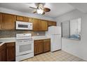 Kitchen with wood cabinets, white appliances, and tiled floor at 6200 Peregrine Ct, Orlando, FL 32819