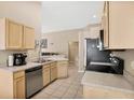 Cozy kitchen with stainless steel appliances and light wood cabinets at 120 Casterton Cir, Davenport, FL 33897