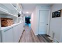 Bright hallway with wood floors, built in white shelving units, and white doors at 2016 West Pkwy, Deland, FL 32724