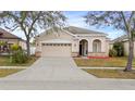 Tan house with a two-car garage and neatly landscaped yard at 2078 Marsh Hawk Dr, Orlando, FL 32837