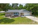 Single-story home with stone exterior, attached garage, and grassy yard at 1365 Indian Rock Ct, Deltona, FL 32725