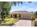 Lovely single-Gathering home showcasing a lush front lawn, mature trees, and a brick-paved driveway at 1569 Victoria Way, Winter Garden, FL 34787