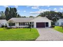 Single-story house with a paved driveway, landscaped yard, and a burgundy garage door at 26608 Racquet Cir, Leesburg, FL 34748
