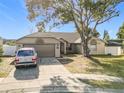 Single-Gathering house with a driveway and large tree in front at 933 El Lago Ter, Winter Springs, FL 32708