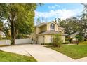 Two-story house with beige exterior, lush landscaping, and a large driveway at 1175 Brentwood Dr, Clermont, FL 34711