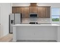 Modern kitchen featuring stainless steel appliances, white quartz countertops, and sleek brown cabinetry at 27469 Black Kite Ave, Howey In The Hills, FL 34737